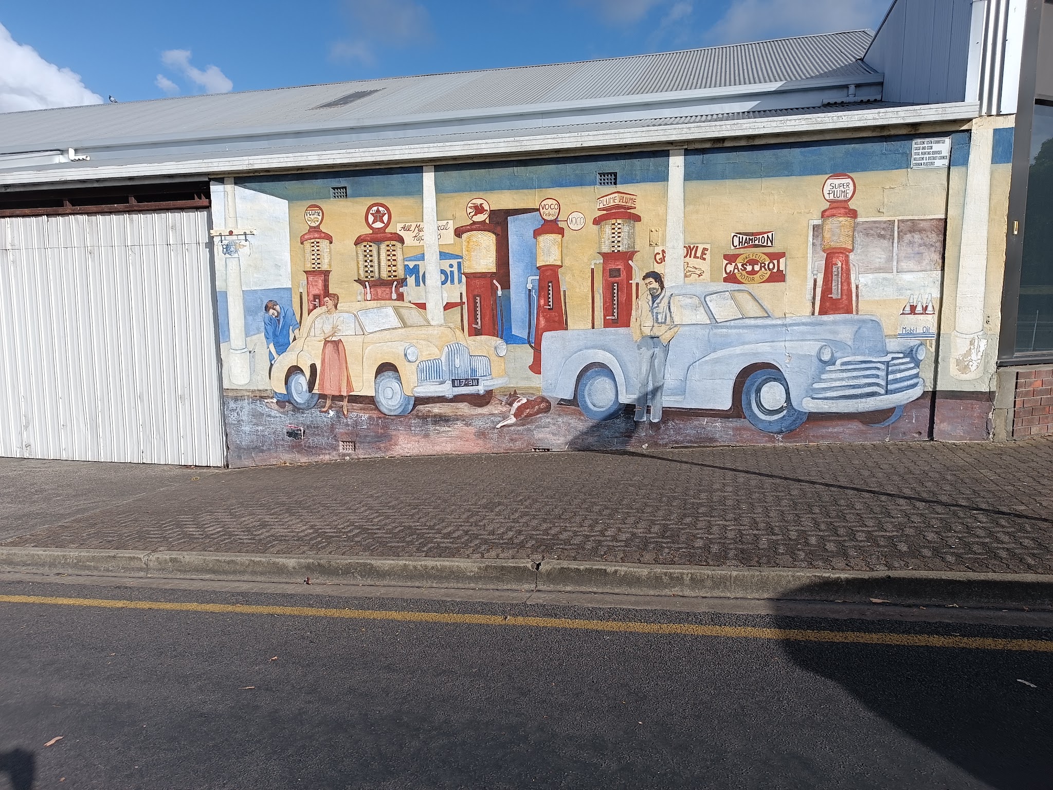 The old service station mural painted on the side of the Trusted Automotive building, showing vintage petrol bowsers and two classic cars